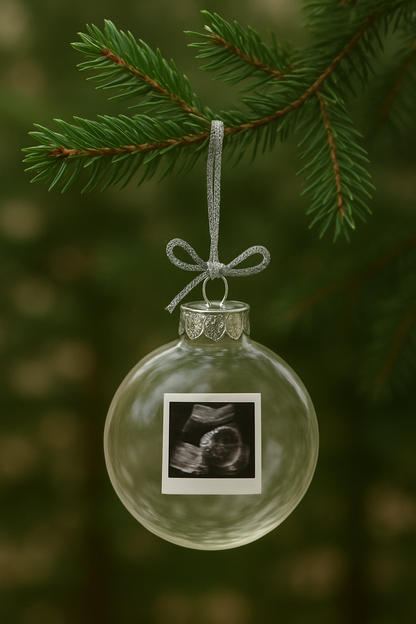 Clear Christmas ornament with ultrasound photo on a green tree branch