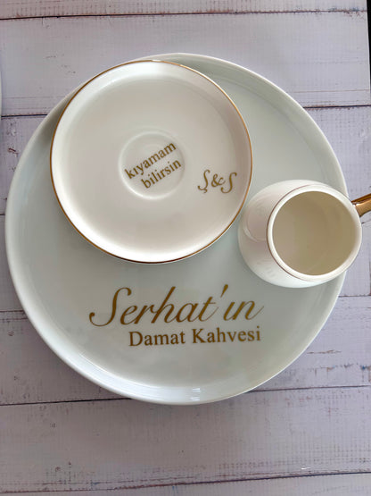 Ceramic cup and saucer with 'Serhat'in Damat Kahvesi' text on a white wooden surface