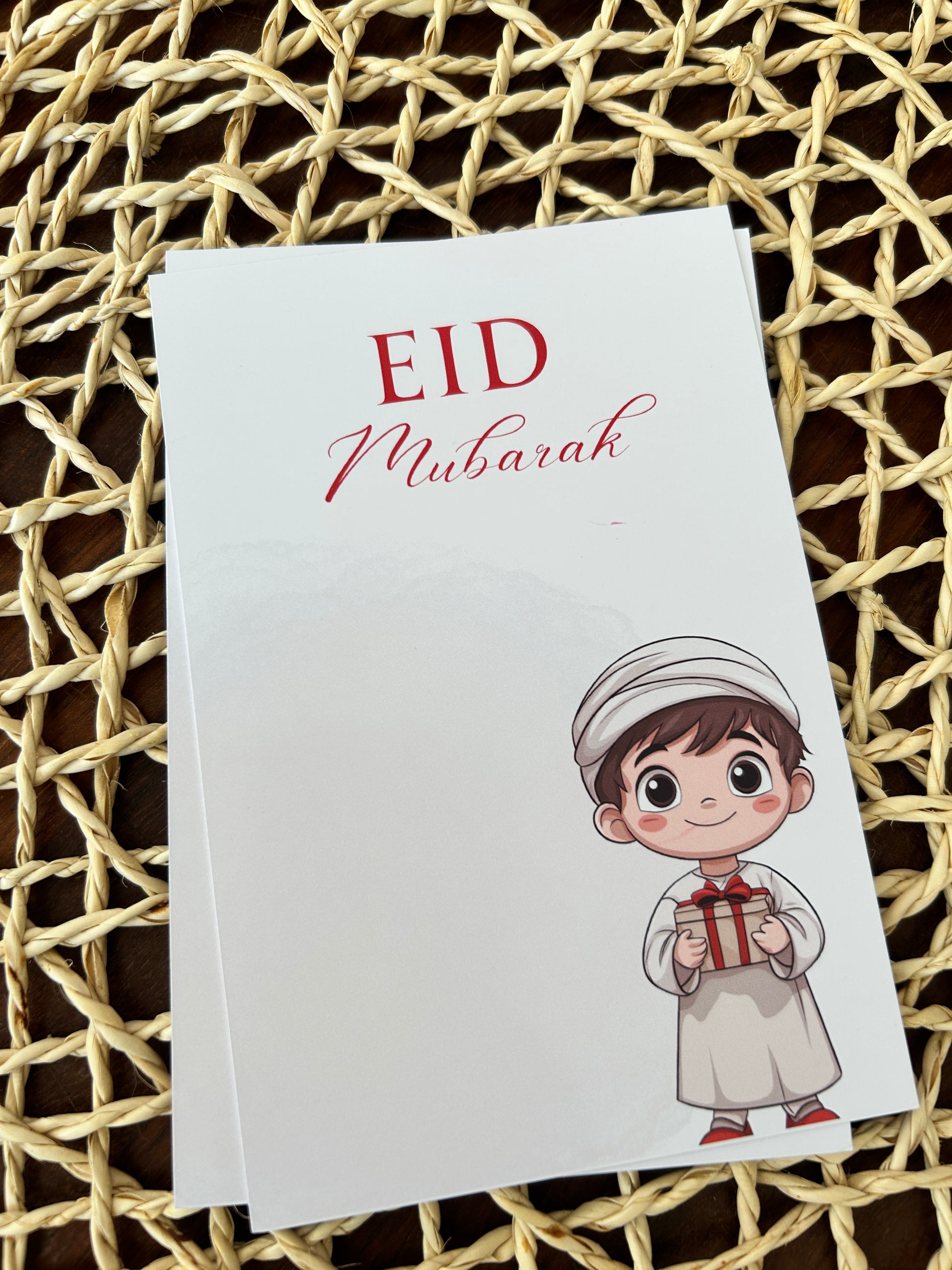 EID Mubarak card with a cartoon character on a woven surface