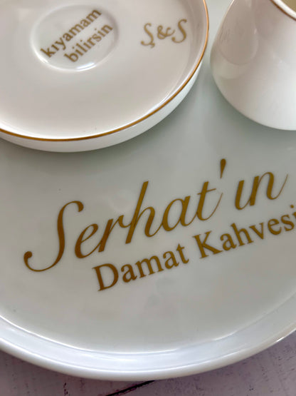 White ceramic plate with gold text 'Serhat'in Damat Kahvesi' and a small dish in the background.
